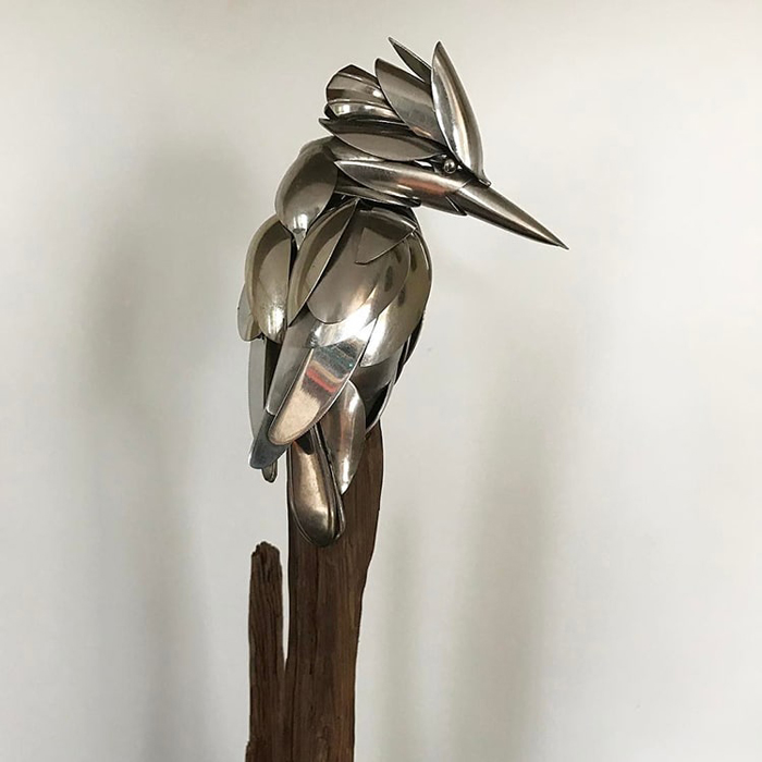 metal bird sculpture perched on wood