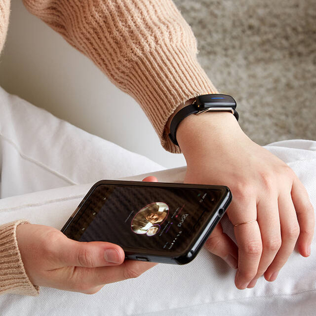 Womans Hand Wearing a Vibrating Bracelet and Holding a Phone